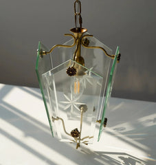 Glass pendant light with brass fixtures on a white surface with shadows