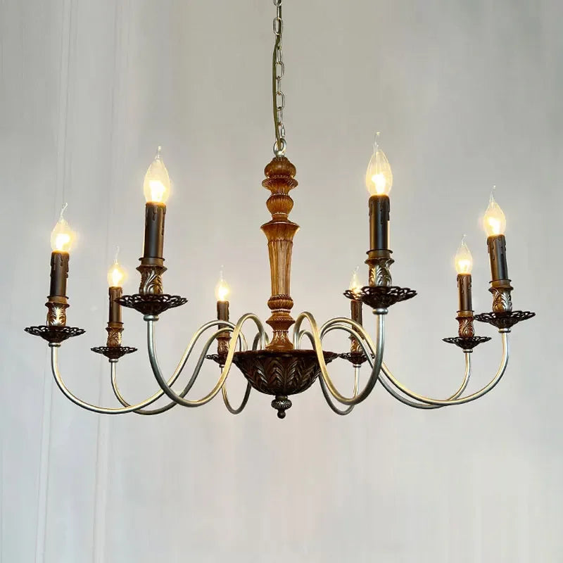 A detail shot of a white candelabra style chandelier showcasing its distressed finish and the candle-shaped bulbs.