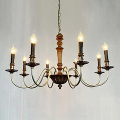 A detail shot of a white candelabra style chandelier showcasing its distressed finish and the candle-shaped bulbs.