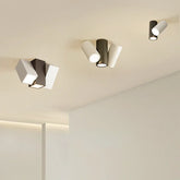 Modern black and white cylinder spotlights mounted on a ceiling, with adjustable heads.