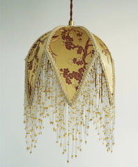 Decorative lamp with floral pattern and beaded fringe on a plain background