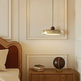 Decorative lamp hanging above a wooden nightstand with books and a globe in a bedroom setting.