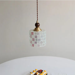 Small pendant light with patterned shade and wooden bulb holder on a neutral background