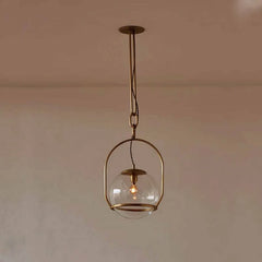 A black metal frame surrounds a clear glass globe pendant light, suspended by a chain from a ceiling mount.