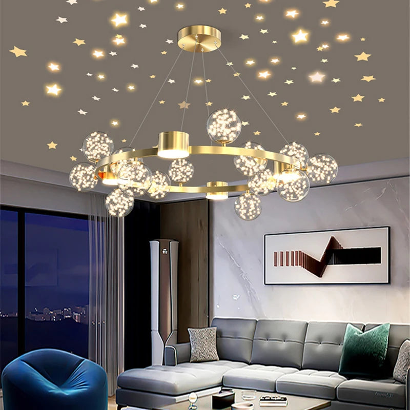 A modern gold chandelier with crystal-filled glass orbs and a starburst design hangs in a living room with star decals on the ceiling.