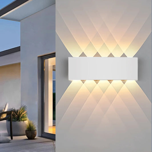 White geometric wall sconce mounted on a grey wall, casting upward and downward light patterns.