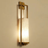Brushed gold rectangular wall sconce with a fabric shade, mounted on a cream-colored wall.