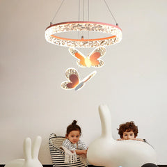 A pink crystal ring pendant light with three butterfly accents hanging over two children in a room.