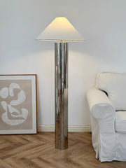 Floor lamp in a room with a sofa and artwork on the wall.