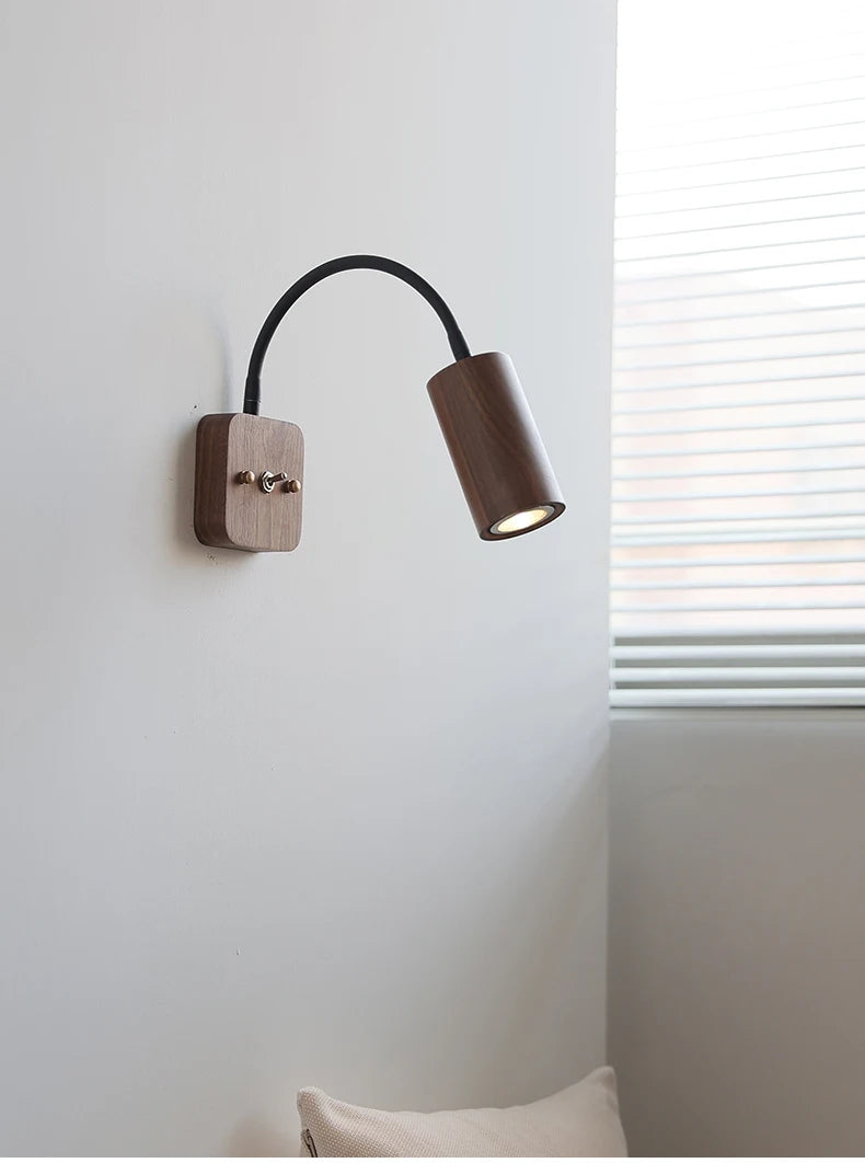 Wall-mounted lamp with brown shade and wooden base on a white wall.