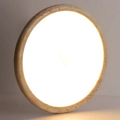 Close-up of a circular flush mount ceiling light, highlighting the rough, natural texture of its stone-like frame.