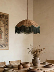 Woven rattan dome pendant light with a dark fringe hanging above a dining table setting
