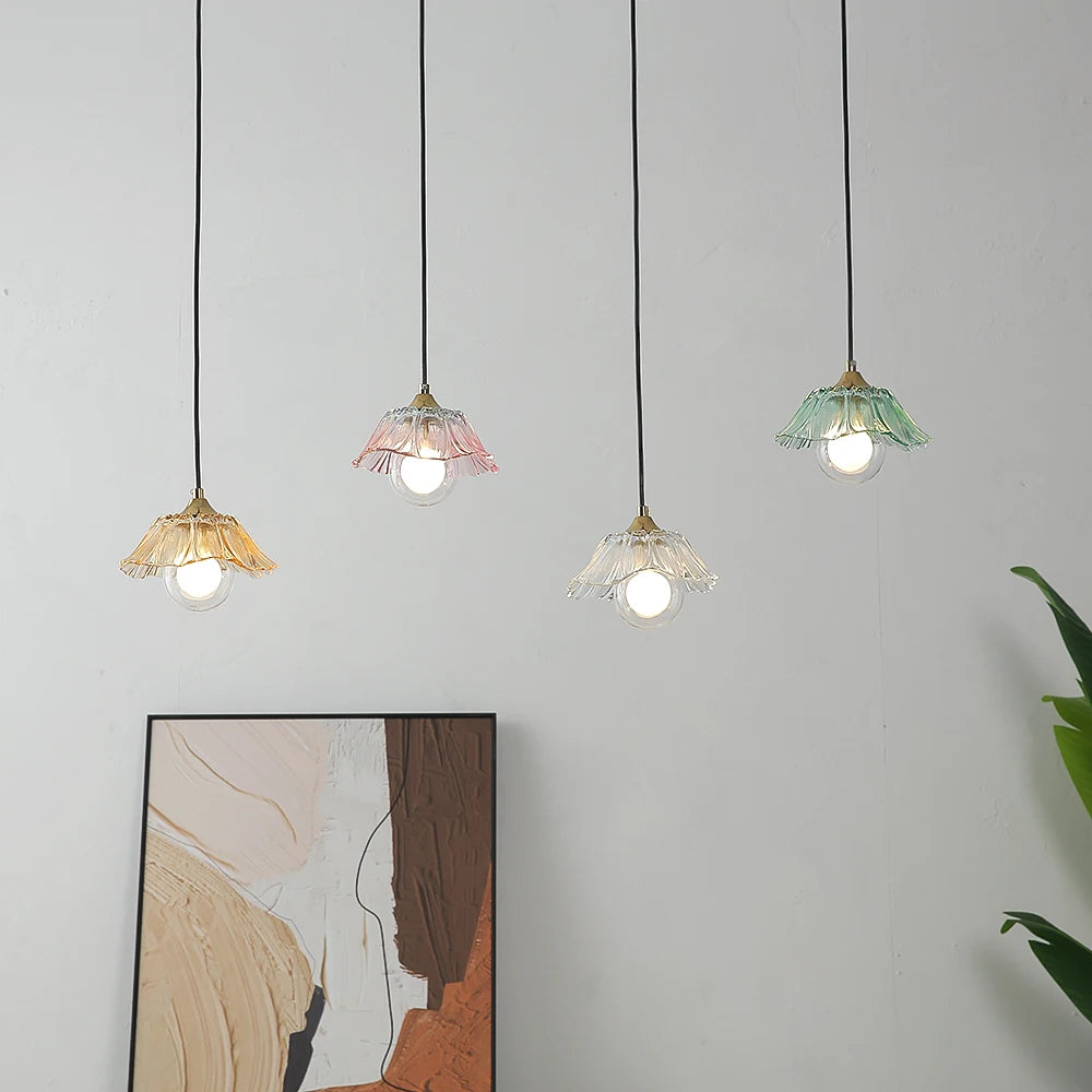 Close-up view of four colorful glass pendant lights hanging against a white wall.