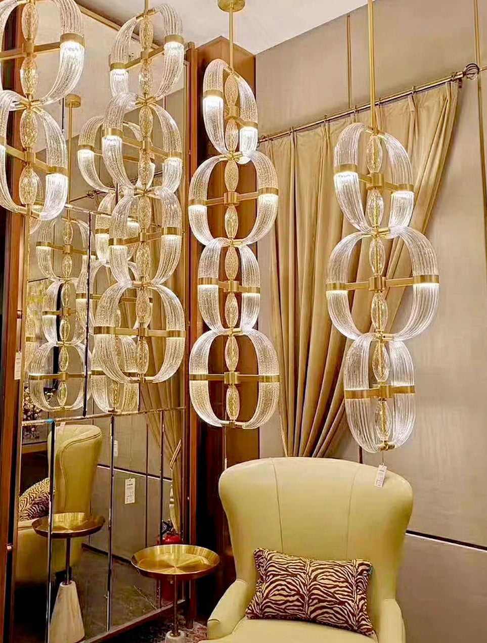 Luxurious interior with gold and glass chandelier, yellow armchair, and patterned pillow.