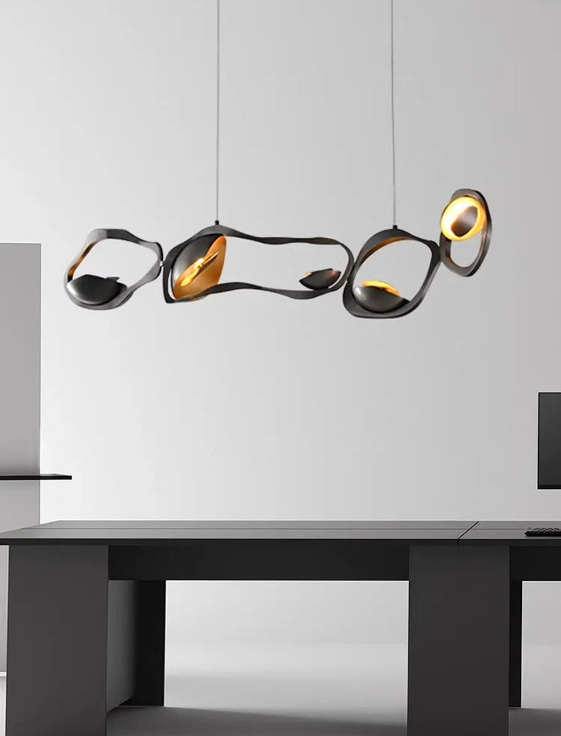 Modern pendant light fixture hanging above a desk with a minimal white background