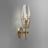 Single clear glass crystal wall sconce with a brushed gold frame mounted on a grey wall.