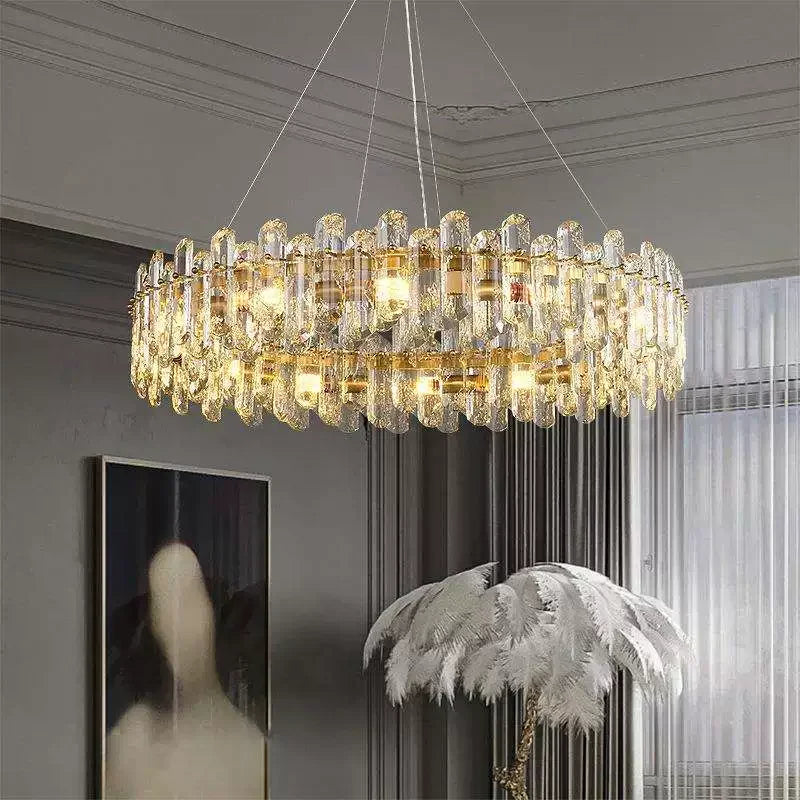 A large, circular gold chandelier adorned with numerous clear crystal teardrop-shaped elements, suspended from the ceiling in a well-lit room.