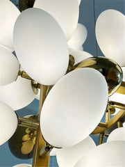 Close-up of a modern chandelier with white glass shades and gold metal accents against a blue background.