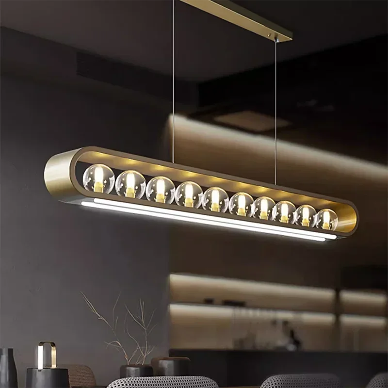 Close-up of a modern gold pendant light featuring clear glass spheres and a brushed gold finish, suspended by thin wires.