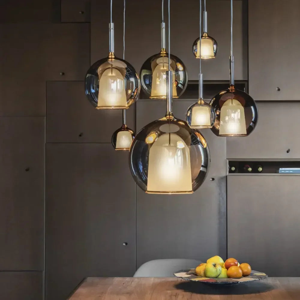 A cluster of globe pendant lights with rose gold finish and clear glass shades hanging over a wooden table.