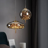 Two glass pendant lights with gold accents, filled with warm LED lights, hanging against a dark wall.
