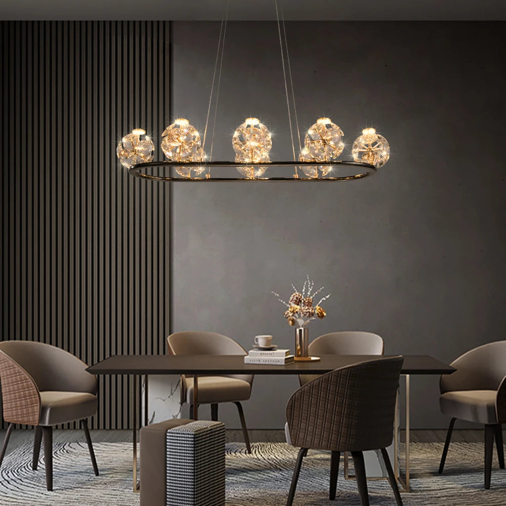 Gold linear pendant light with multiple crystal orb lights hanging over a dining table.