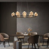 Gold linear pendant light with multiple crystal orb lights hanging over a dining table.