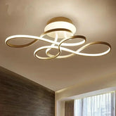 Ceiling view of a modern gold swirl flush mount light with integrated LED lighting against a white ceiling.