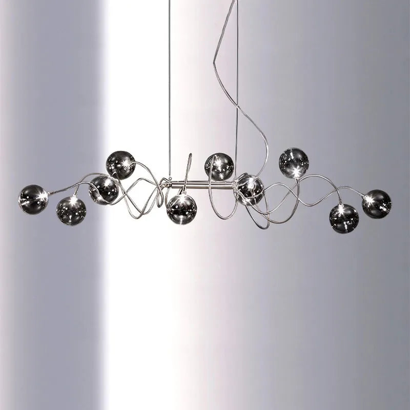 Chrome spiral wave pendant light with multiple smoky gray glass globes suspended against a white background.