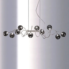 Chrome spiral wave pendant light with multiple smoky gray glass globes suspended against a white background.