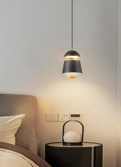 Modern pendant light hanging above a bedside table with a lamp in a bedroom setting.