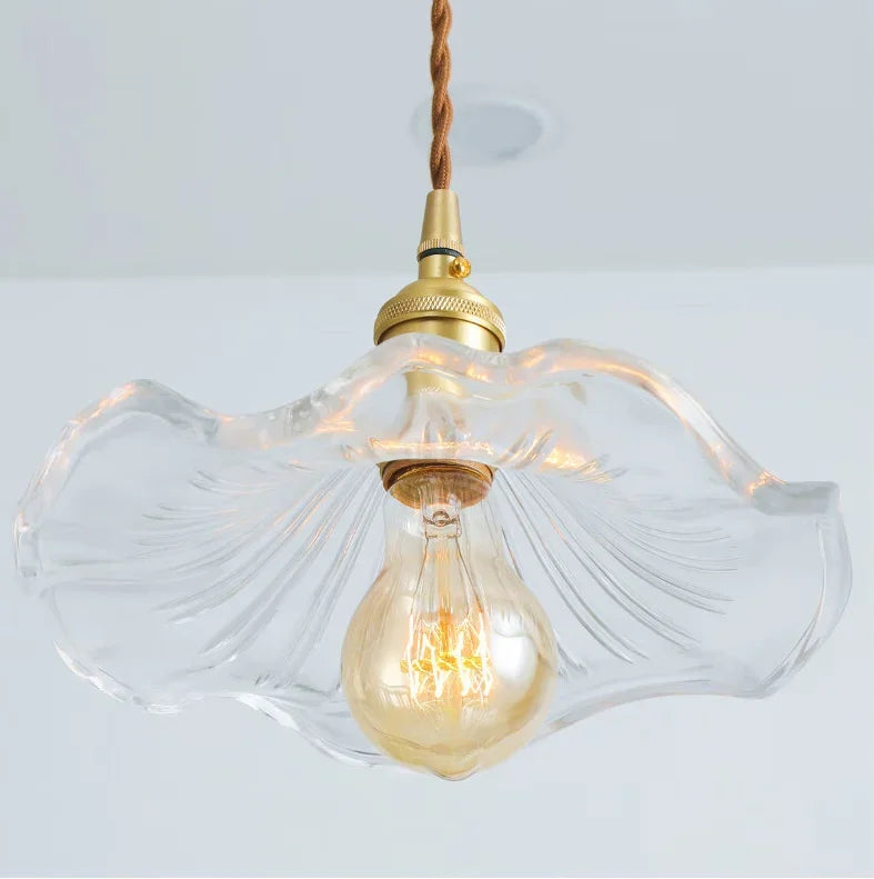 Decorative pendant light with clear glass shade and gold bulb on a white background