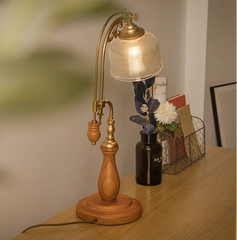 Wooden and brass table lamp on a wooden surface with a blurred background