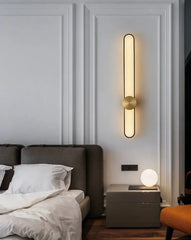 Modern wall sconce in a bedroom setting with a bed and nightstand.