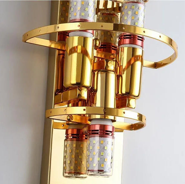 Gold wall-mounted light fixture with cylindrical design on a white background