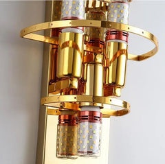 Gold wall-mounted light fixture with cylindrical design on a white background