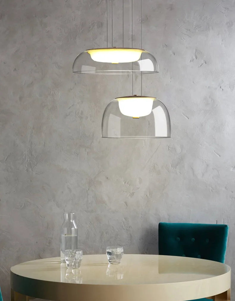Modern pendant lights hanging above a round table with a gray wall background
