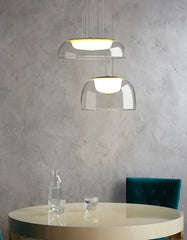 Modern pendant lights hanging above a round table with a gray wall background