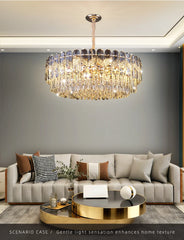A gold crystal chandelier with a layered design, suspended above a dining table in a well-lit room.