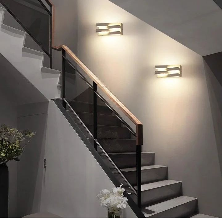 Staircase with modern wall lights and a flower vase on a step.