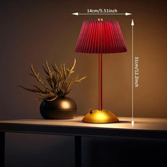 Red lamp with gold base on a table next to a plant, with measurements indicated.