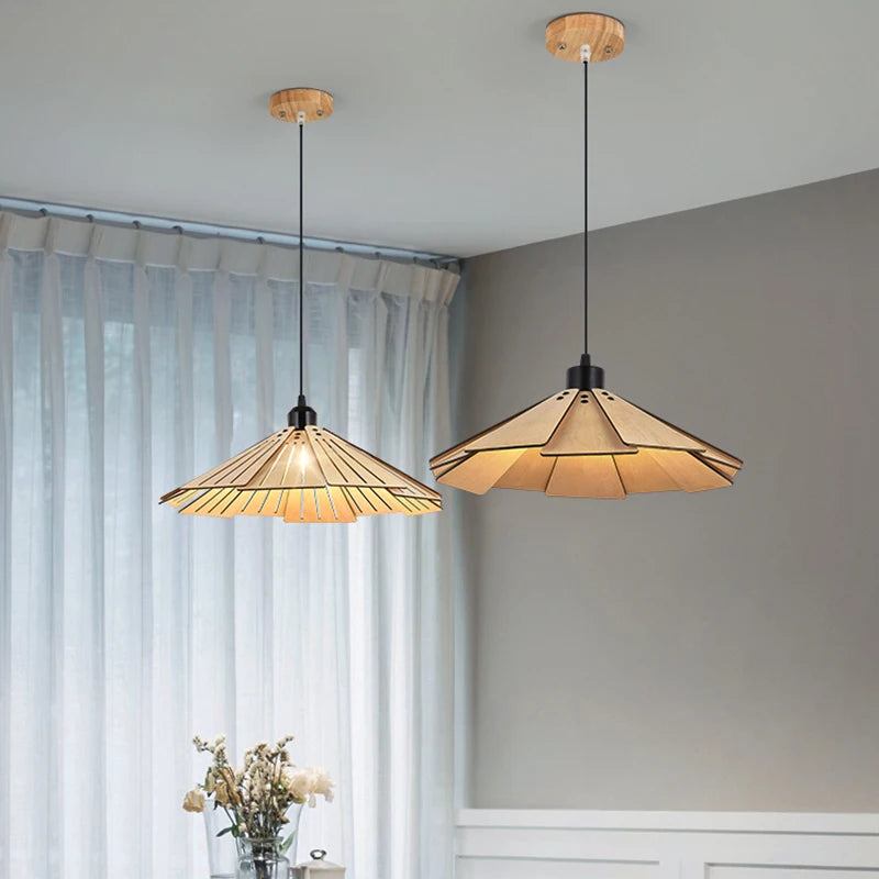 Two wood tiered geometric pendant lights hanging in a room with sheer curtains.