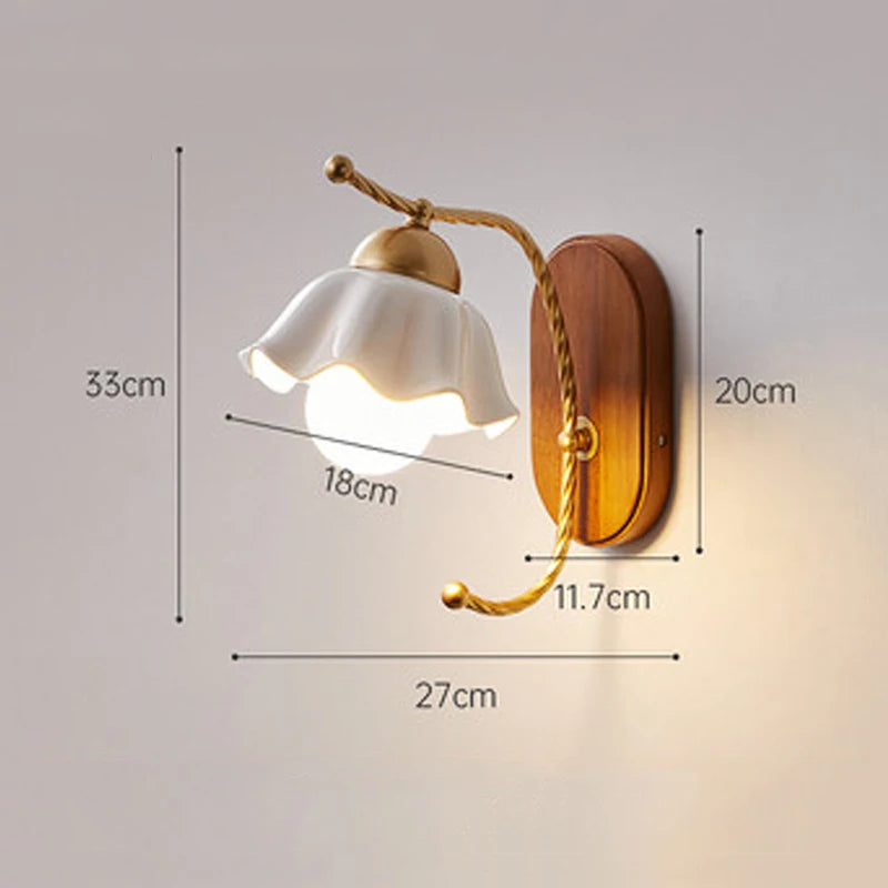 A wall sconce with a white ceramic flower shade, showing dimensions: height 33cm, shade width 18cm, base height 20cm, arm length 27cm, base width 11.7cm.