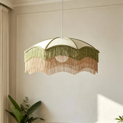 White fabric pendant light with green and peach tassels hanging from a ceiling