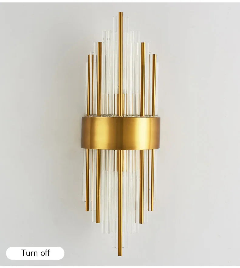 Gold wall sconce with cylindrical glass elements on a light gray background