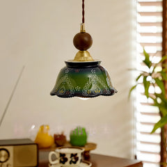 Green ceramic bell pendant light with hand-painted floral details, suspended indoors.
