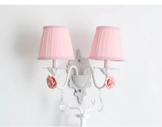 White double wall sconce with pink pleated fabric shades, adorned with pink roses and crystal droplets.