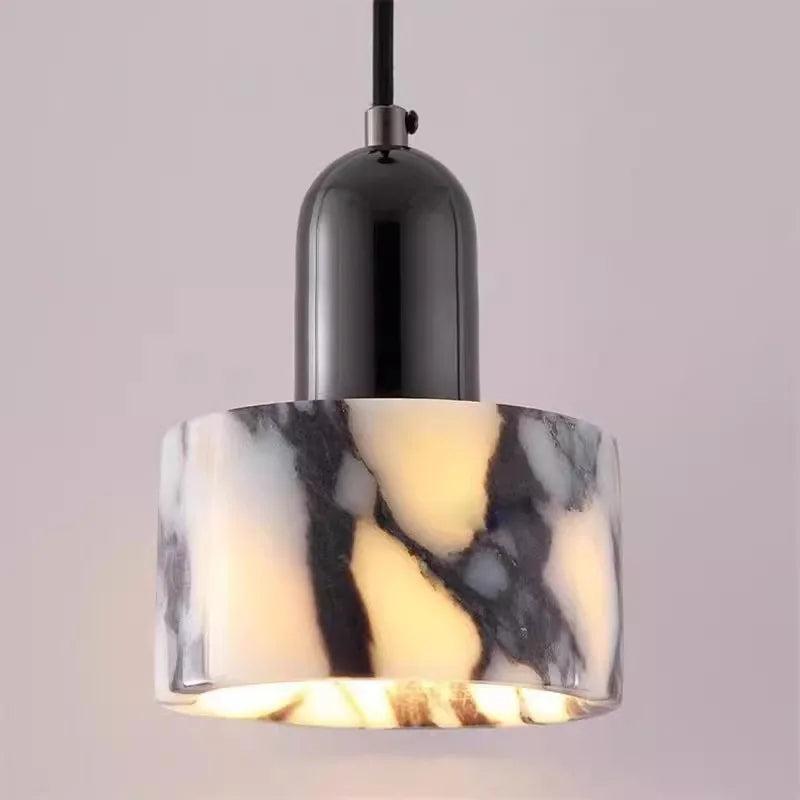 Detailed view of a marble pendant light with a black cap and frosted glass bottom, illuminated from within.
