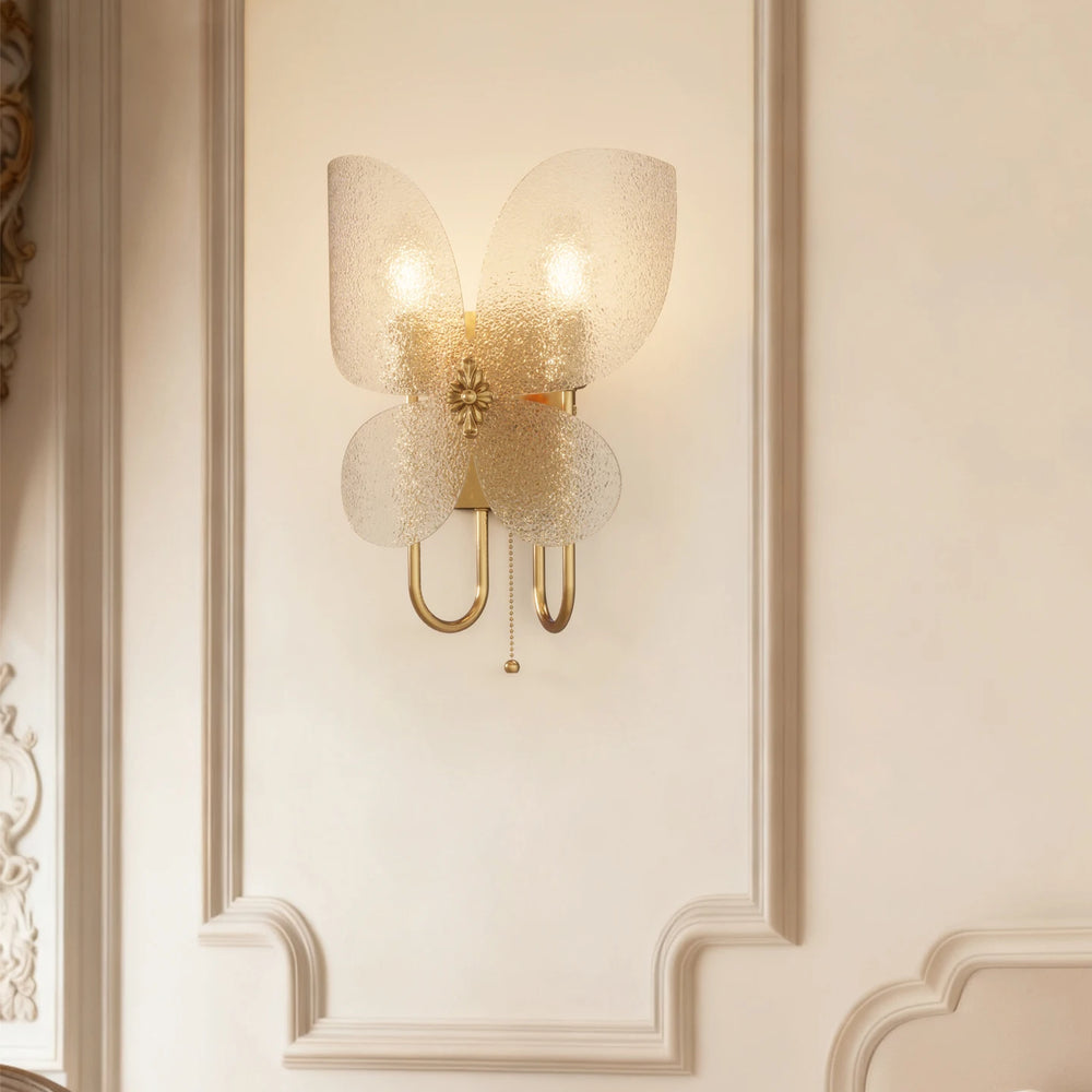 A view of the gold butterfly wall sconce against a detailed white wall molding, emphasizing its design.