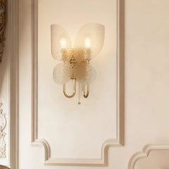 A view of the gold butterfly wall sconce against a detailed white wall molding, emphasizing its design.